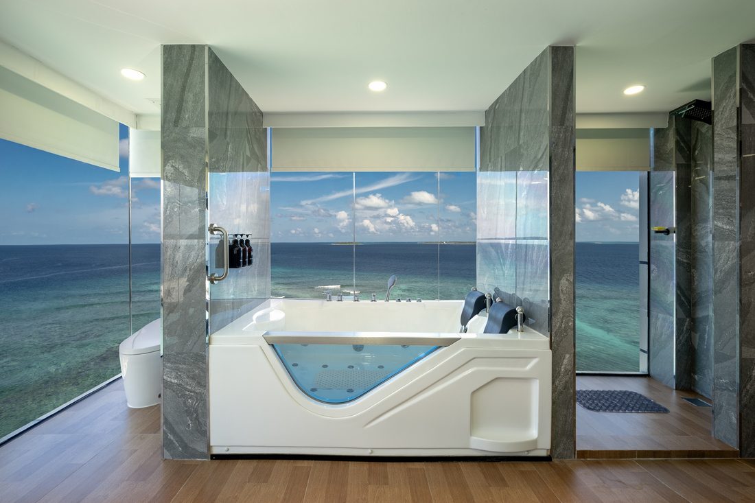 Bathroom with a tub facing the reef through full-height windows