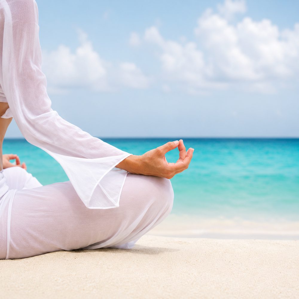 Hands resting in a mudra during meditation on the beach