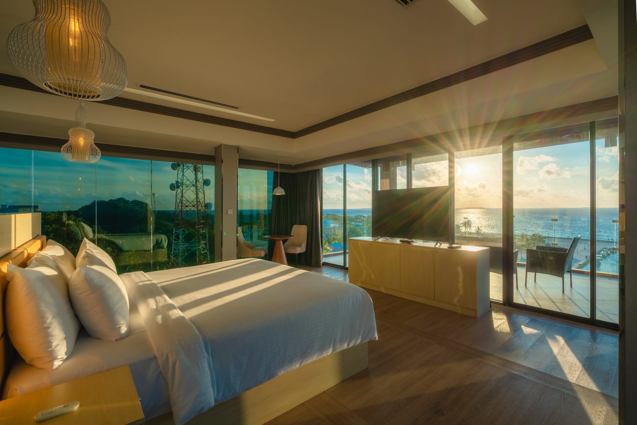 Hotel room with floor-to-ceiling windows and the sun setting over the ocean